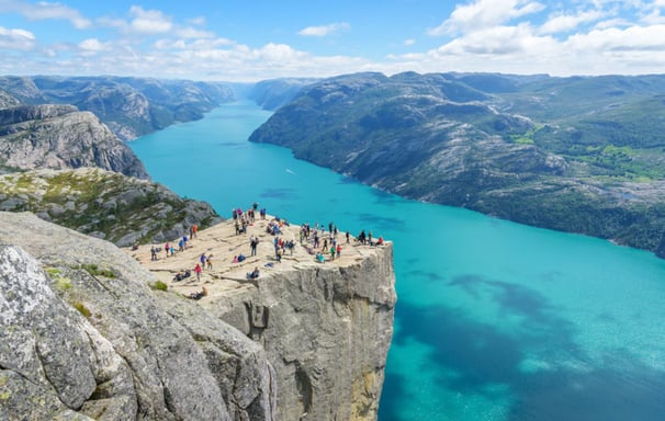 a group of people standing on a cliff overlooking a lake