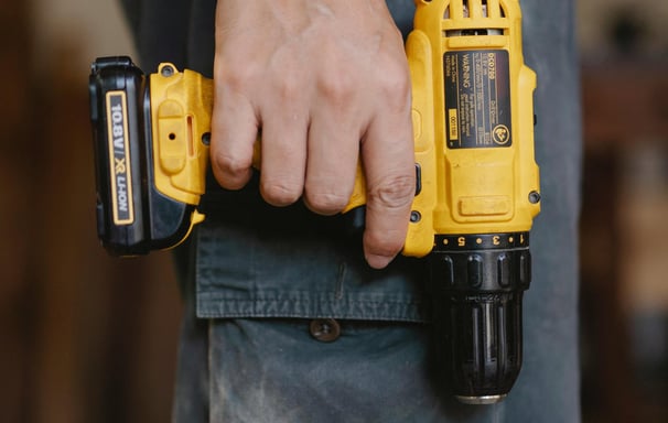 a man holding a cordless drill in his hand