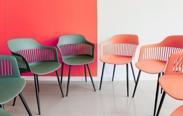 Grey and pink office chairs in a semi circle. Reprensenting facilitation for workshops.