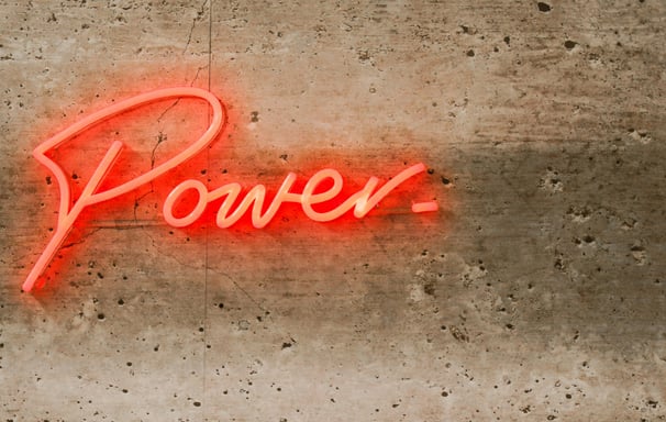 Team Support & Engagement represented by light 'Power' neon on concrete wall. 