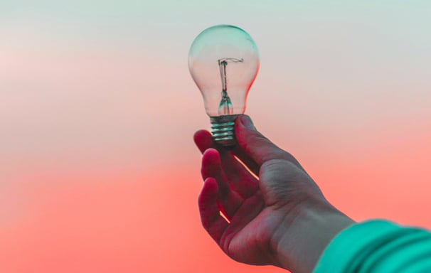 Person holding lighbulb, representing ideas and messaging services.