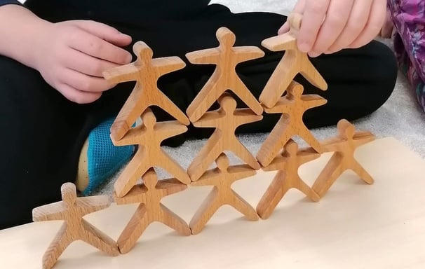Kind baut Holzpüppchen-Pyramide