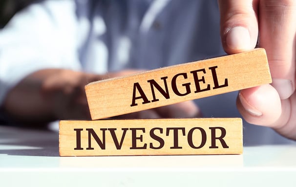 a person holding a wooden block with the words angel investor