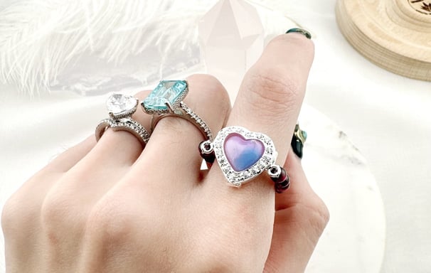 Gold-toned chain accessories featuring heart-shaped links and enamel flower charms in white and blac