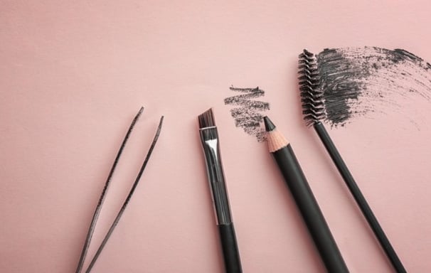 a few brushes and a brush are on a pink surface