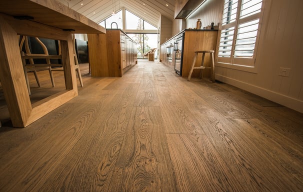 Kitchen and dining area features custom hardwood floors and cabinetry, warm, modern space.