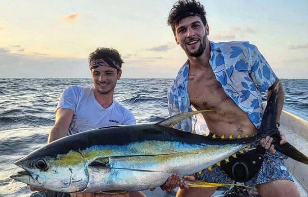 Two happy fishermen holding a large yellowfin tuna on a deep-sea fishing charter in Zanzibar