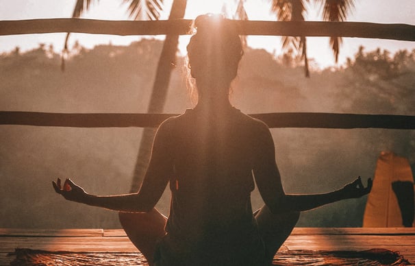 Frau meditiert im Schneidersitz im Sonnenaufgang