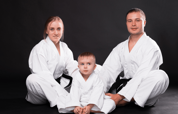 a man and woman in karate gear posing for a family photo