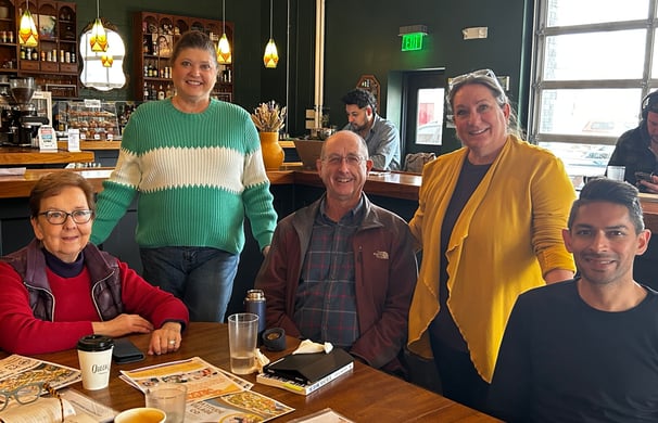 Group of smiling men and women at a table in a coffee house