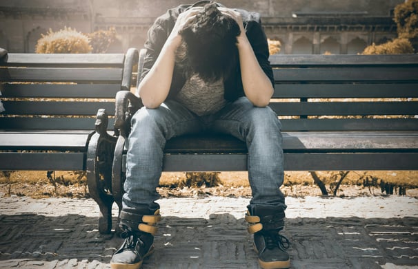 man sitting on a bench stressed out.  man is autism masking