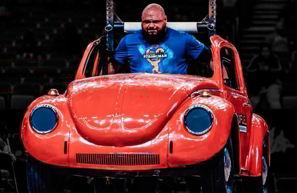 a man in a blue shirt is holding a red car