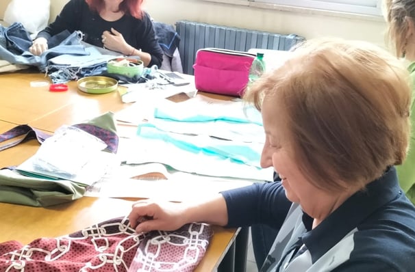 a woman is sitting at a table with a bunch of clothes
