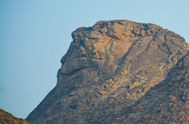 a bird flying over a mountain with a blue sky