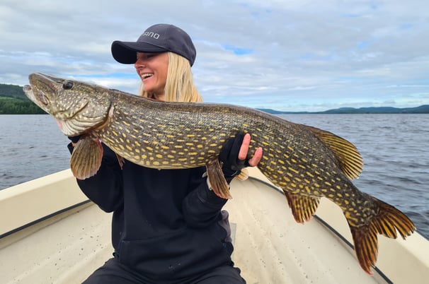 Girl angler proudly displays her personal best catch: a pike.