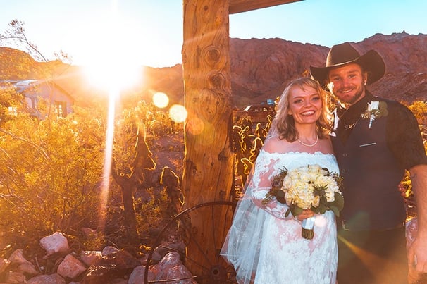 a man and woman in cowboy attire standing in front of a wooden structure