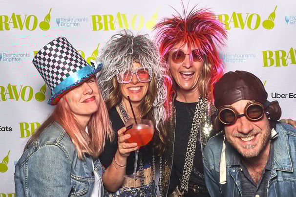 Group of people posing in Get The Picture photo booth with fun wigs props and glasses at corporate party
