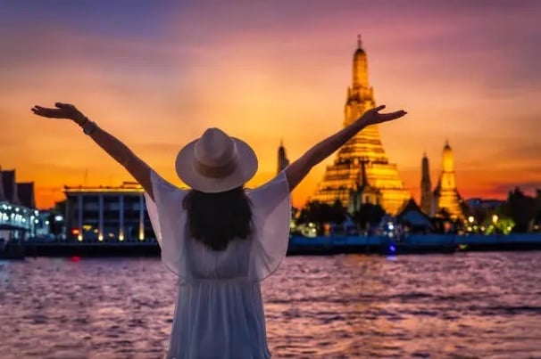 a woman in a white dress and hat with her arms up and hands up in