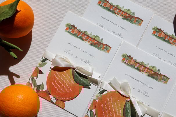 a bunch invitations with the orange house and some oranges on a table