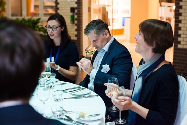 Ein Gast, der an einem Tisch Weißwein riecht.