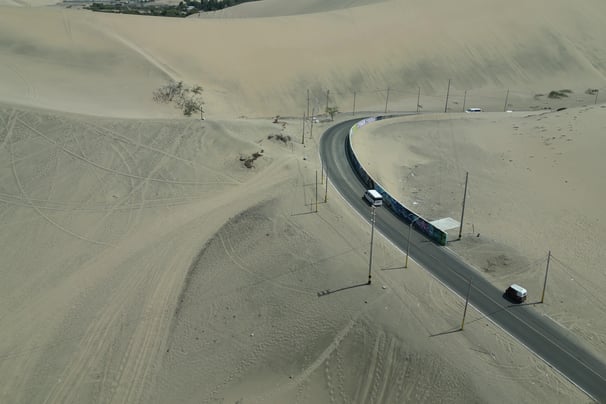 Aerial Drone Shot of a vehicle passing through the desert of Huacachina Oasis Peru