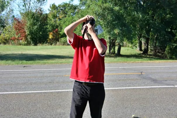 Homme avec t-shirt rouge prenant une photo.