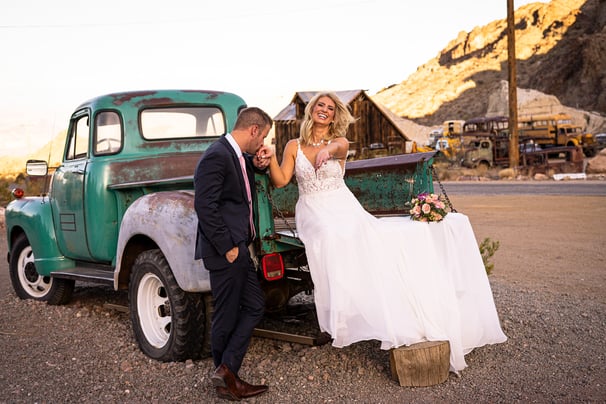 a bride and groom standing in front of a truck