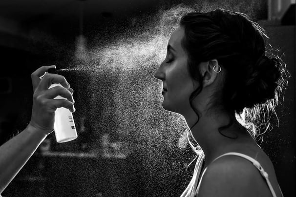 a woman is spraying makeup setting spray for a polished look
