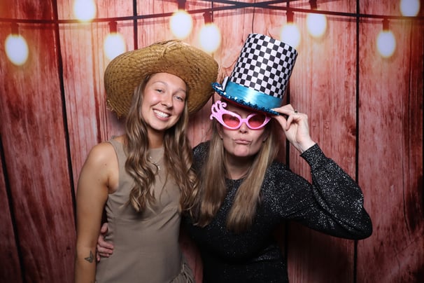 Two young ladies posing for a photograph on the get the picture photo booth at a corporate party with fun hats