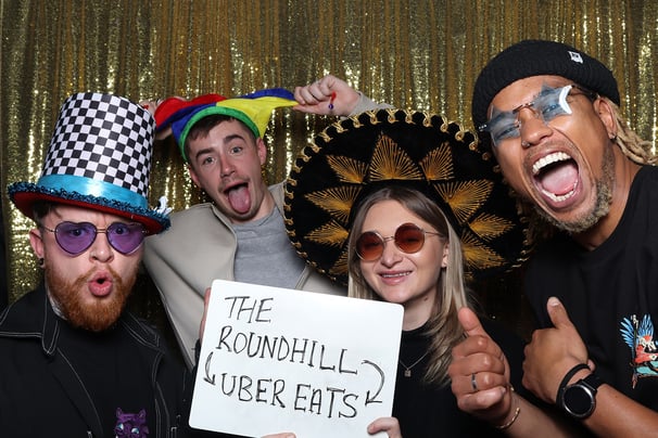 Excited guests posing energetically for the get the picture vintage Photo Booth at a private party while wearing stylish prop