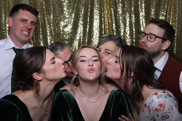 Guests at a wedding event using the Get The Picture photo booth with everyone kissing a bridesmaid