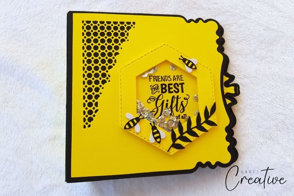 Yellow handmade photo album with a hexagonal window featuring bees and sequins. Text reads, "Friends