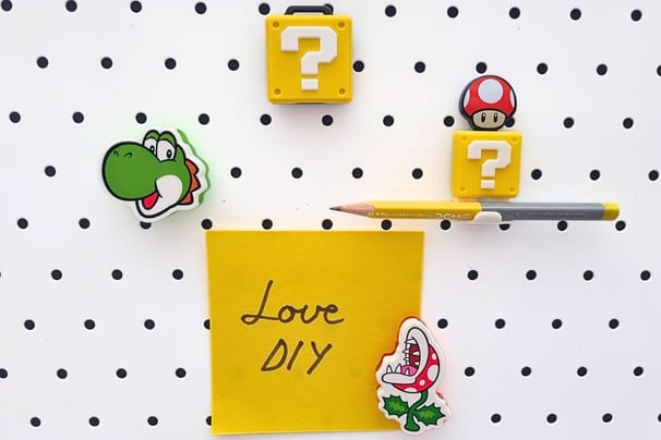 Magnetic board features colorful Mario-themed magnets: Yoshi, mushroom, and piranha plant. A yellow