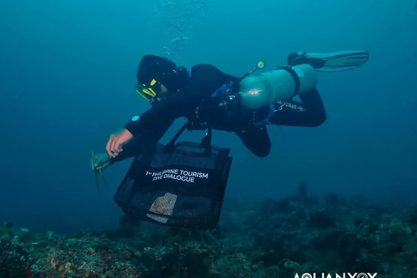 Scuba diver Chu Taga Isla outdoors picking up trash with tourism bag