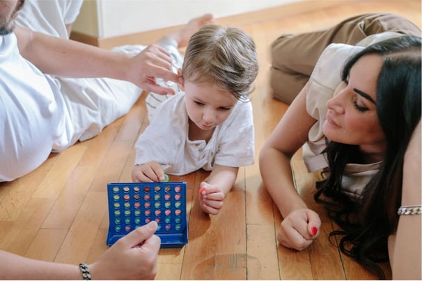 Mother and father claying Connect Four with their young child