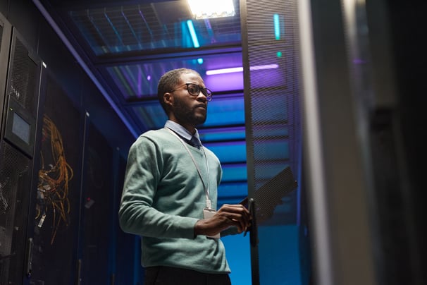 a man in a server room with a laptop