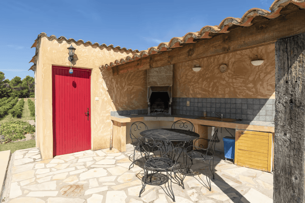 a patio with a table and chairs and a red door