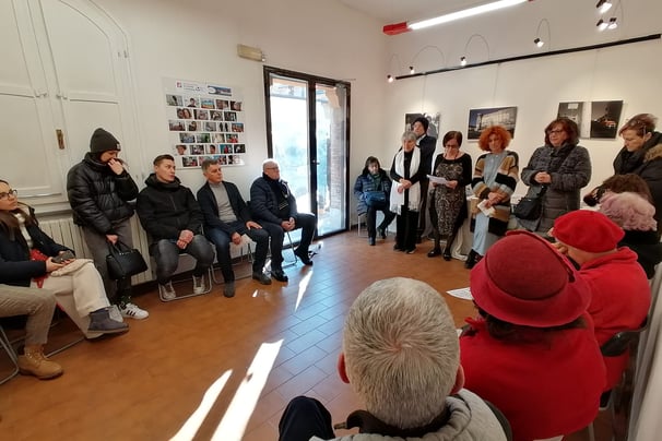 a group of people sitting in a circle with a man in a red hat