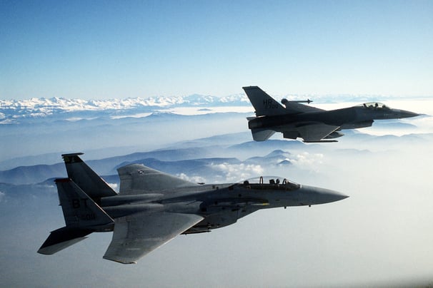 two jets are flying in the sky above the clouds