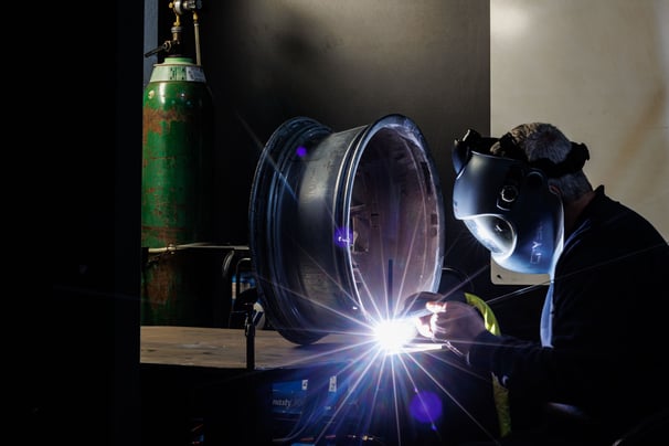 a man in a gas mask welding a pipe