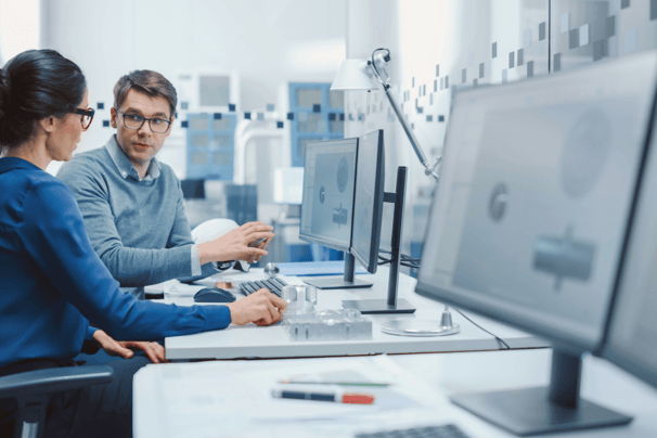 a man and woman sitting at a desk with a computer monitor