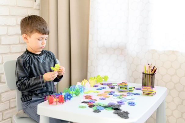 a young boy sitting at a table with a cupcake