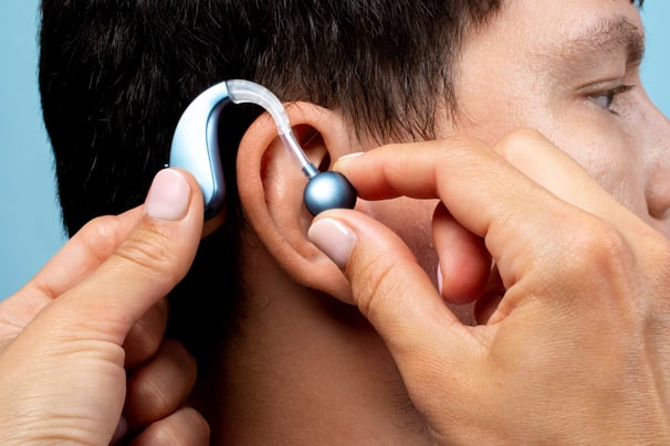 a man with a silver earpieces is putting a silver earpiece on his