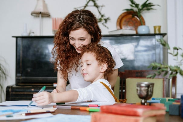 A mother and young child drawing with coloured pens.
