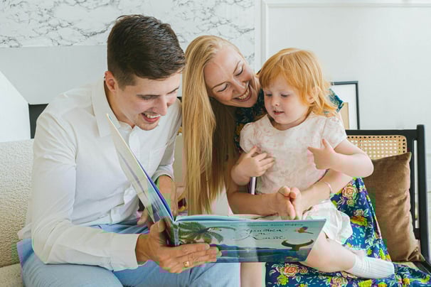 A mother and father reading a children's picture book to a child.