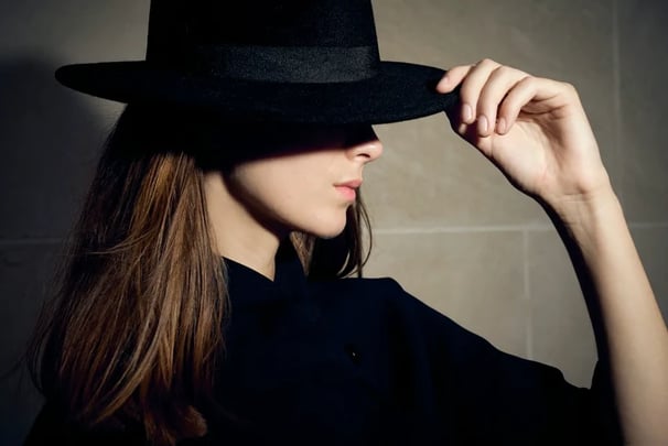 trait fin d’une femme posant de profil avec chapeau, ombre sous les yeux, éclairage au flash