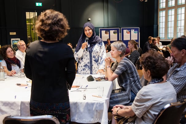 Eine muslimische Frau stellt dem Moderator während eines Workshops eine Frage.