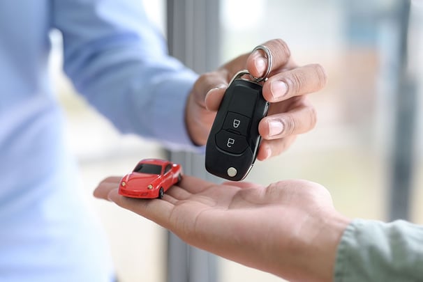 a person holding a car keychain and a small toy car
