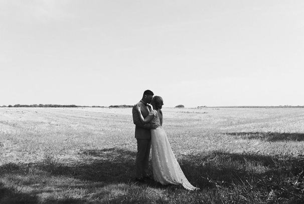 Séance couple en noir et blanc dans un champ après un mariage.