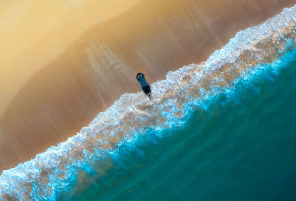 a person standing on a beach with a surfboard. arbab naimat kasi balochistan gawadar